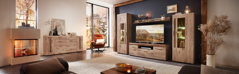 Vackert vardagsrum med v&auml;ggm&ouml;bel, sideboard och &ouml;ppen spis