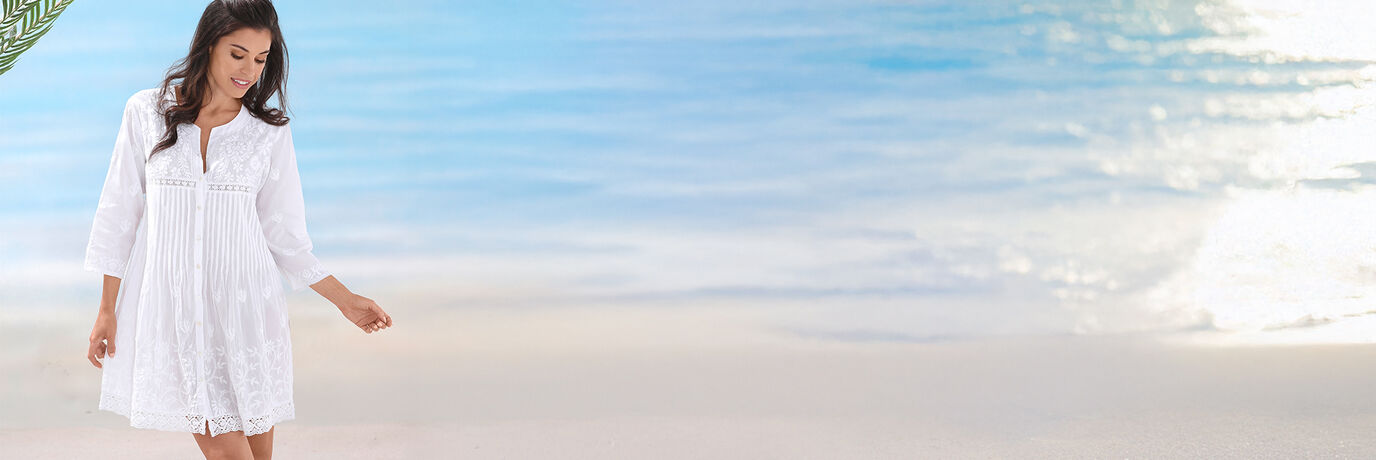 Kvinna i vit kl&auml;nning p&aring; stranden