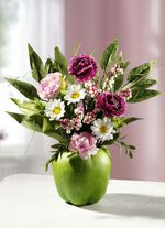 Ranunculus arrangemang i en &auml;ppelkruka 