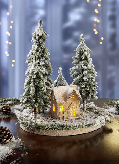 Upplyst vinterstuga med granar 