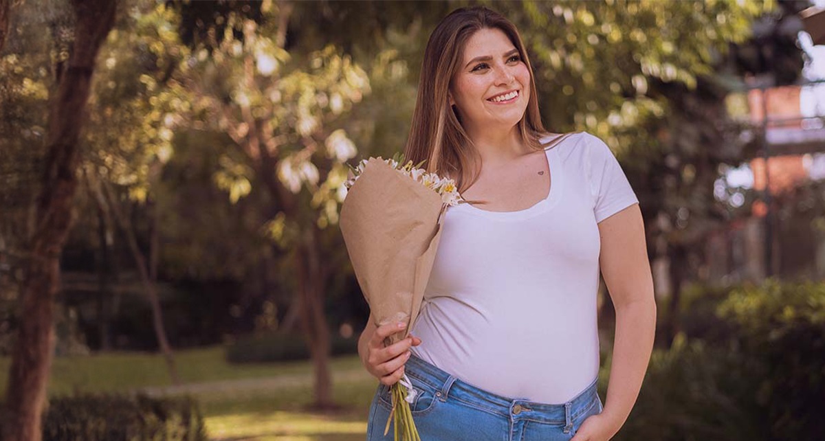 Kvinna i vit T-shirt med blommor i handen